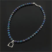 designer strand of black culture pearl necklace with solid silver vintage stirrup inspired charm on black background..