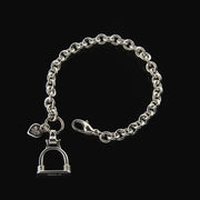 Designer solid silver heavy weight chain bracelet with vintage stirrup inspired large charm on black background.