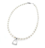designer cultured pearl necklace with vintage solid silver stirrup design charm on white background.
