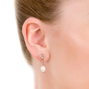 close up shot of model wearing designer rose gold and cultured pearl ascot drop earrings on white background 