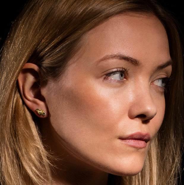 model wearingdesigner gold knotted strap stud earrings . 