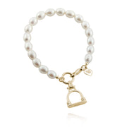 designer solid gold stirrup and cultured pearl bracelet on a white background.