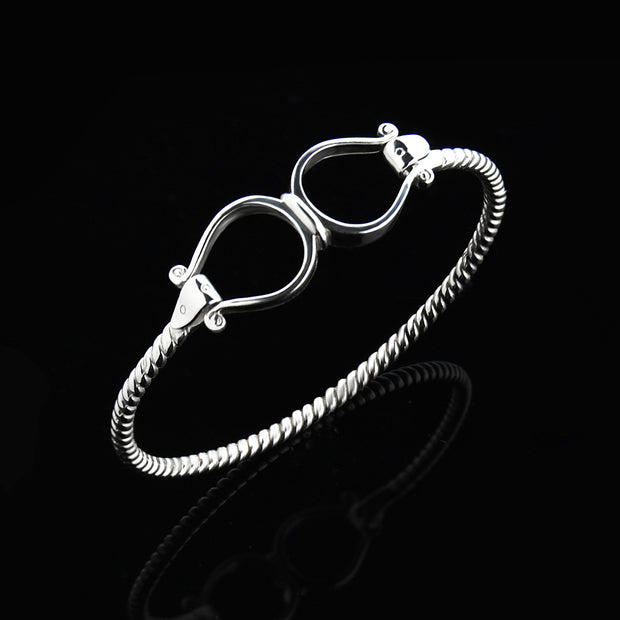 Solid silver double western stirrup opening bangle on black.