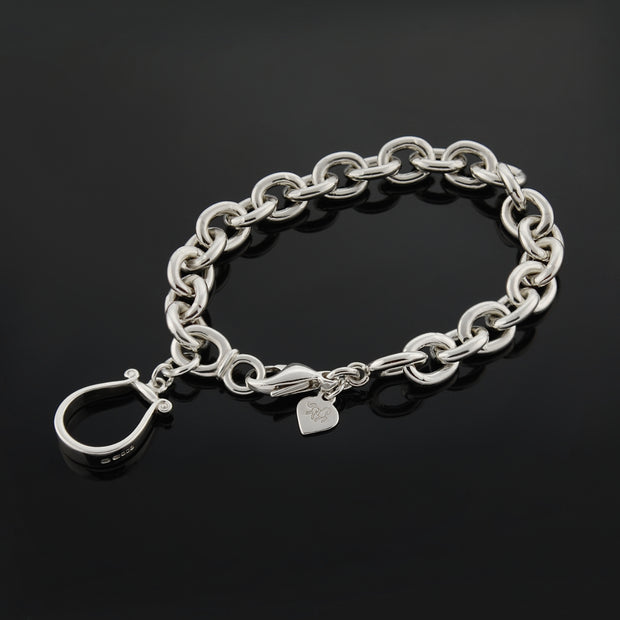 Designer solid silver western stirrup heavy chain bracelet on black background.