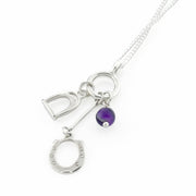 Designer solid silver horseshoe, stirrup and amethyst charm necklace on white background.