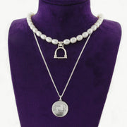 Designer Horse coin and badminton pearl necklaces on dark purple display bust.