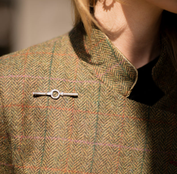 model wearing designer solid silver equestrian inspired stocpin brooch on tweed jacket