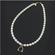 Designer solid 9ct gold vintage stirrup and cultured pearl necklace on black background