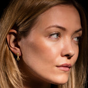 model wearing designer solid 9ct yellow gold horse bit inspired drop earrings on white background.