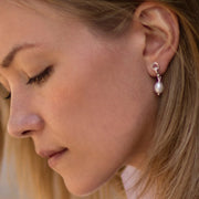 model wearing designer solid silver and cultured pearl ascot drop earring on white background.