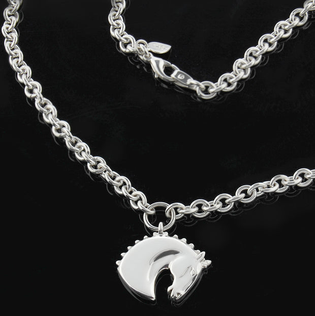 Designer solid silver carved horsehead necklace on heavy chain on black background.