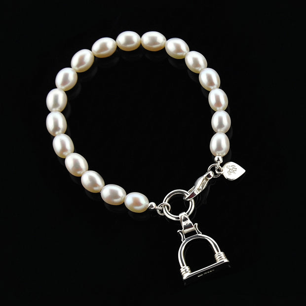 designer silver and cultured pearl bracelet with vintage stirrup charm on black.