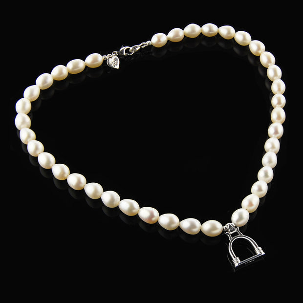 designer cultured pearl necklace with vintage solid silver stirrup design charm on black background.