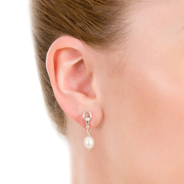 close up of model wearing designer solid silver and cultured pearl ascot drop earring on white background.